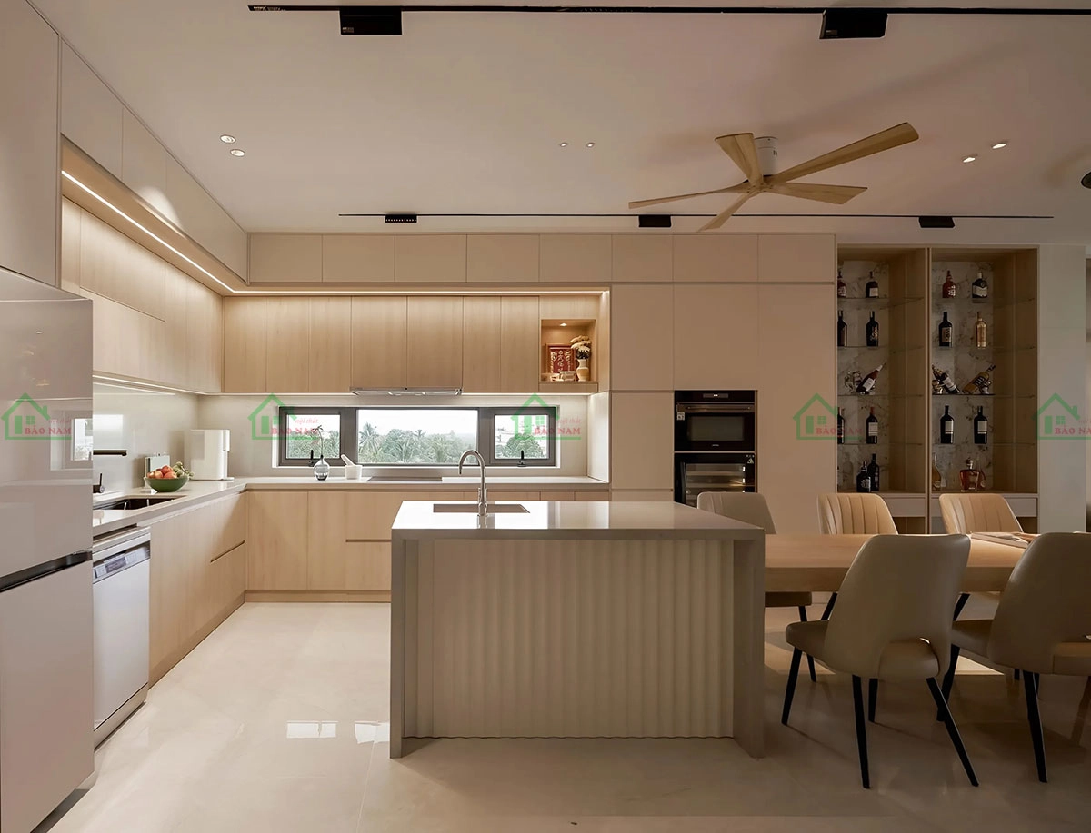 Tủ bếp chữ L kết hợp với đảo bếp nhỏ gọn, tạo không gian nấu nướng tiện nghi và hiện đại.