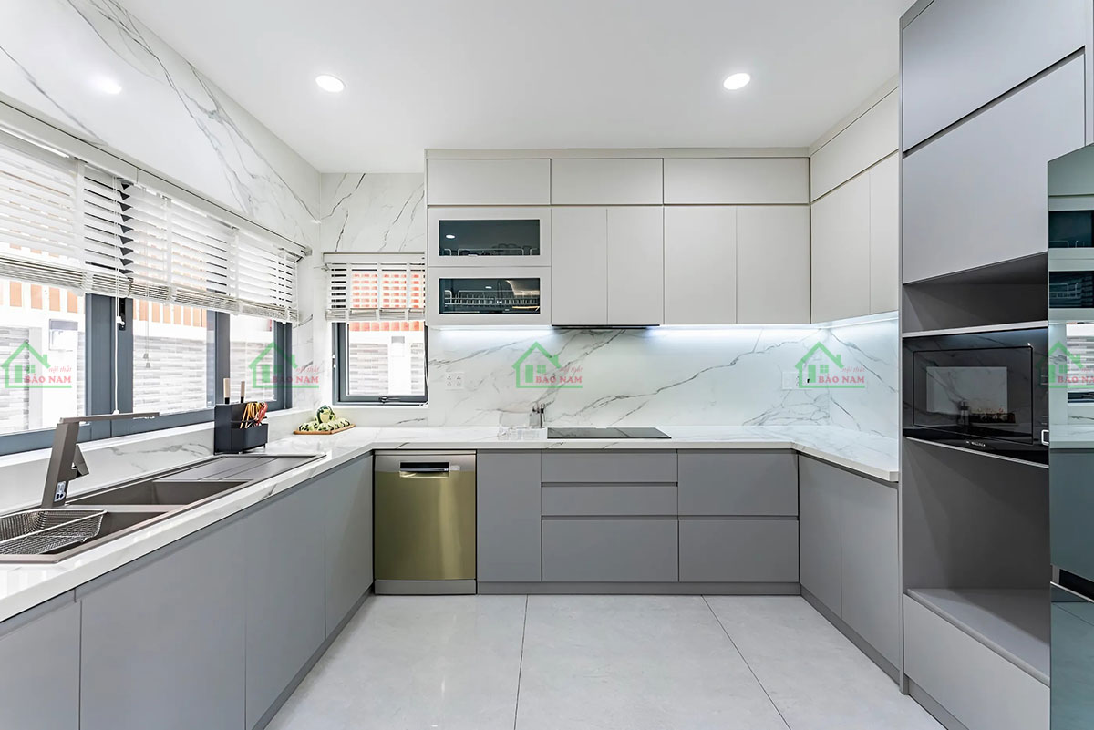 Bàn đá và ốp tường sử dụng Đá Granite trắng sáng bóng, dễ vệ sinh và tạo cảm giác sạch sẽ cho không gian bếp.