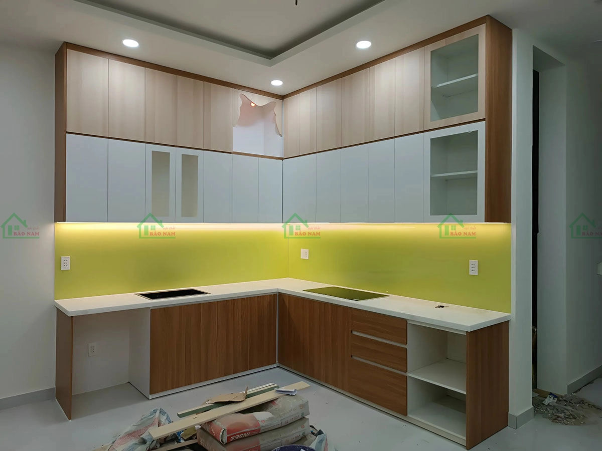 Đội ngũ kỹ thuật lắp đặt đang hoàn thiện tủ bếp gỗ MDF tại không gian bếp.